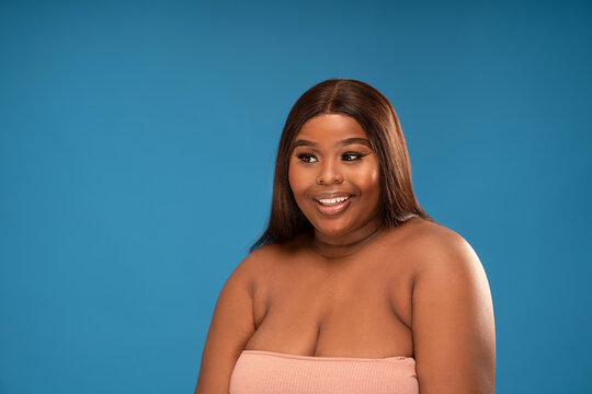 Beauty portrait of african young woman with smile and glamour makeup looking at the camera, posing on blue studio background.