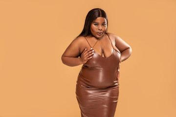 Sexy Plus Size african Woman posing in brown leather dress, looking at the camera. Fashionable...