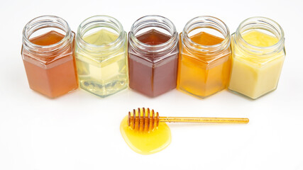 spoon with fresh honey and pollen on the background of jars with different types of honey. organic vitamin food