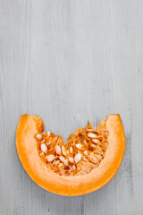 Fresh organic pumpkin slice on light wooden background top view with copy spac