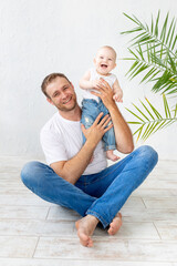 Fototapeta premium dad with baby son in his arms laughing on a white background, happy fatherhood and family, father's day