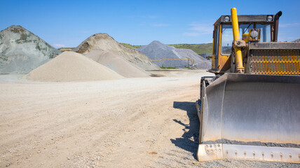 A bulldozer on the territory of an asphalt plant. A bulldozer on a background of gravel and rubble...