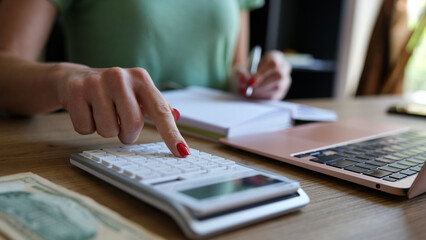 Fototapeta premium Woman hand using a calculator and letter makes note with cost calculation in home office