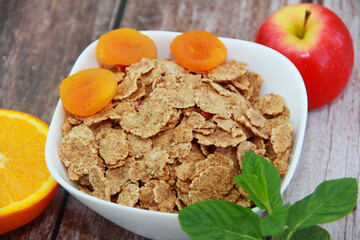 dry diet muesli with fruit in a white plate on a wooden background