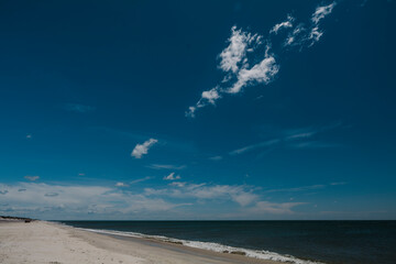 Deserted empty sandy beach in sunshine, blue skies and clouds in Fire Island New York. High-quality photo