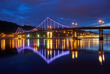 Fototapeta na wymiar Night city landscape. Pedestrian bridge across the Dnieper river, Kyiv, Ukraine