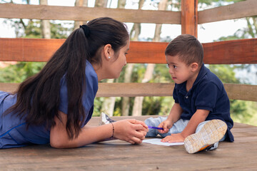 Woman in blue uniform teaching writing to a child with Down syndrome. Children's occupational...