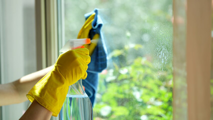 Hands in gloves wash window with rag