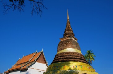 Chedi in Traphang Thong Temple Sukhothai Province, Thailand, with a white viharn in the background.