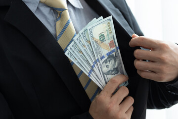 Business man holding dollar cash in hand hiding money in suit. Concept for corruption, finance...