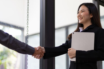 Handshake. Attractive Asian businesswoman with happy smiling face while shaking hands with coworker and agreeing business partnership.