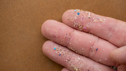 Micro plastic particles on a human finger for scale. Concept for water pollution and global...