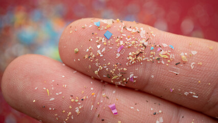 Micro plastic particles on a human finger for scale. Concept for water pollution and global...