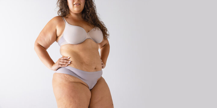 Cropped image of plump, fat female body in underwear isolated over grey studio background. Flyer