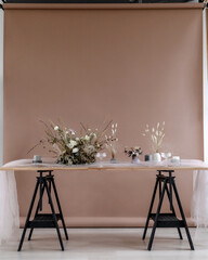 Decorated table with fresh flowers and dried flowers against a paper beige background