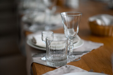 Festive romantic table setting with silverware, gray napkin and white crockery on beige silk tablecloth