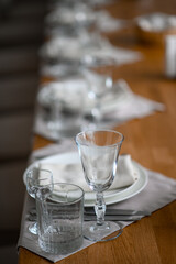 Festive romantic table setting with silverware, gray napkin and white crockery on beige silk tablecloth