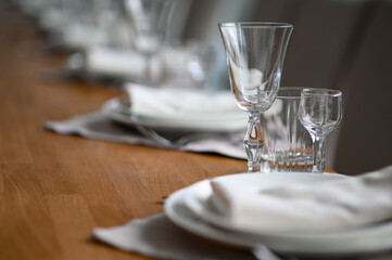 Festive romantic table setting with silverware, gray napkin and white crockery on beige silk tablecloth