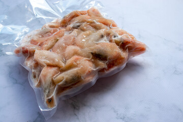 Frozen shrimps in vacuum transparent plastic packaging bag on white table background. Top view,...