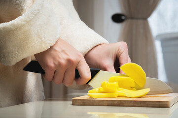 Close-up of female hands cutting fresh peeled potatoes tomatoes on cutting board at home kitchen