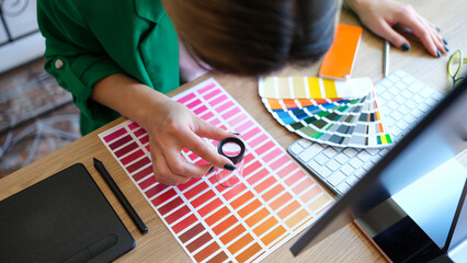 Woman chooses through magnifying glass color and shades on color palette