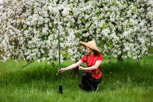 Asian Woman With Sword Training With Tai Chi In The Park, Chinese Martial Arts, Healthy Lifestyle Concept.