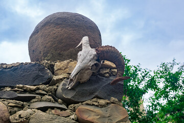 ram skull and a stone ball on top of a fence, an element of a strange landscape design in the countryside
