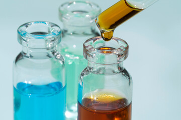 Set of bottles with perfume oils and pipette on lab table.