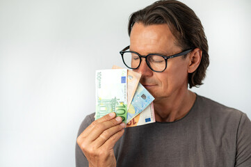 Middle aged man holding money by his face