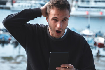 worried young tourist man looking at digital tablet with sea background