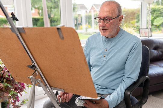 Portrait Of An Older Man Painting With Watercolours. In His Home Studio.