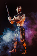 Antique warrior with sword against dark background with smoke