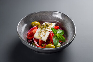 Greek salad with feta cheese and fresh vegetable on grey table side view