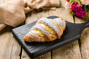 croissant with lemon cream on wooden board on wooden table