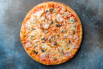 Pizza with ham and mushrooms with cheese and tomato sauce top view on dark blue stone table