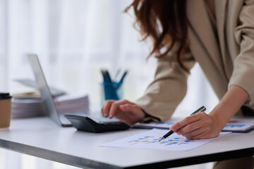 Asian businesswoman working on laptop computer and graph planning a strategy in modern office, Asian woman doing analyzing the financial report, business plan investment, finance analysis concept