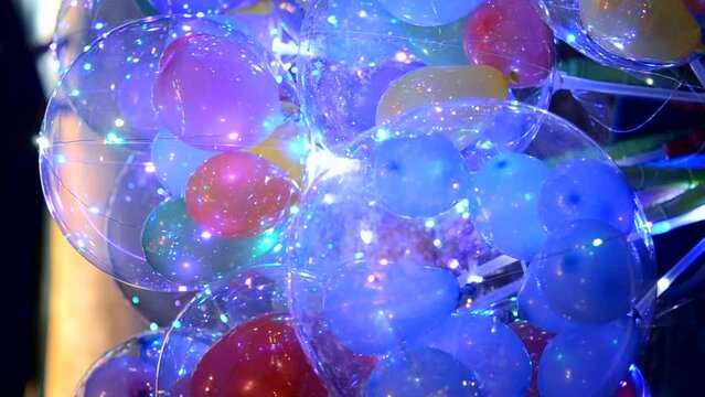 Balloons with luminous garland inside. Abstract colorful background. Many different colorful balloons with flashing garland inside close-up. Holiday, celebrate, New Year, Christmas. Vertical video