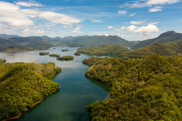 Fototapeta na wymiar Top view of lake and islands among mountains and hills against the blue sky and clouds. Randenigala reservoir, Sri Lanka.