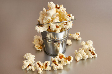 Small bucket filled with popcorn on a gray background.