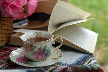 Fototapeta na wymiar A cup of tea, a blanket, flowers, a book in the summer garden.