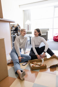 Happy Female Roommates Eating Pizza In College Dorm Room