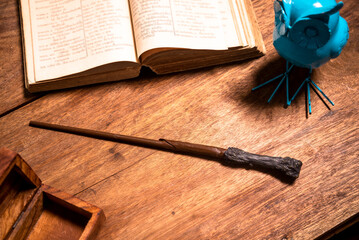 magic wand on a wooden table with an open book. - obrazy, fototapety, plakaty