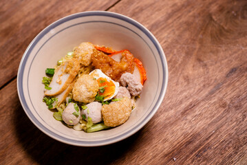 Spicy noodle with boiled egg and grilled red pork. Chinese egg noodles topping slice roasted pork, meatballon plate.