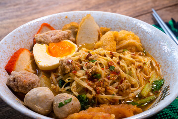Spicy tom yam noodle soup with boiled egg and grilled red pork.