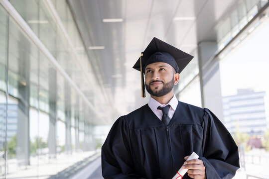Portrait proud young male college graduate in cap and gown