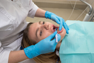 Dentist-hygienist conducts a teeth cleaning procedure for a girl in a dental clinic. Removal of tartar.