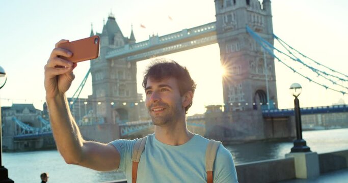 A happy young man smiling and taking a selfie in front of Westminster bridge
