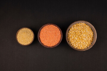 red orange lentil, mung bean, musoorir dal, split chickpea, chana dal in a rock bowl on black background. top view. Indian dal. Grocery product.