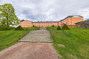 Beautiful exterior of Royal Palace with green lawn and staircase leading up to building in foreground. Sweden.