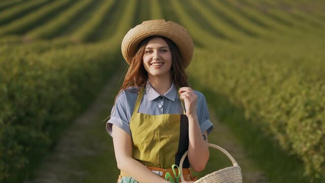 Pretty young woman in a field dressed in the form of a gardener walking with a basket